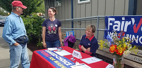 Advocates speaking to an interested person at a tabling event.